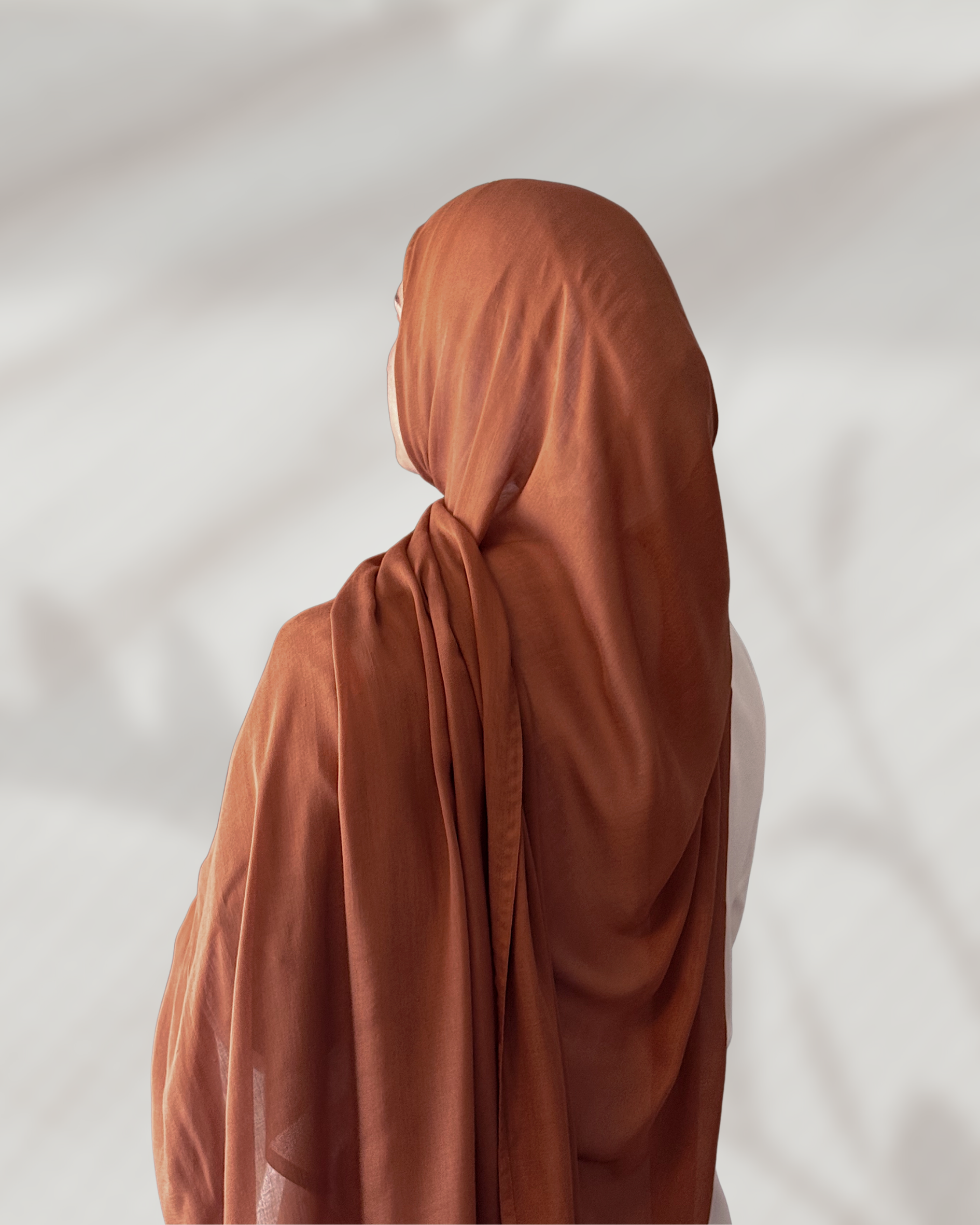 Person wearing a brown hijab against a plain background